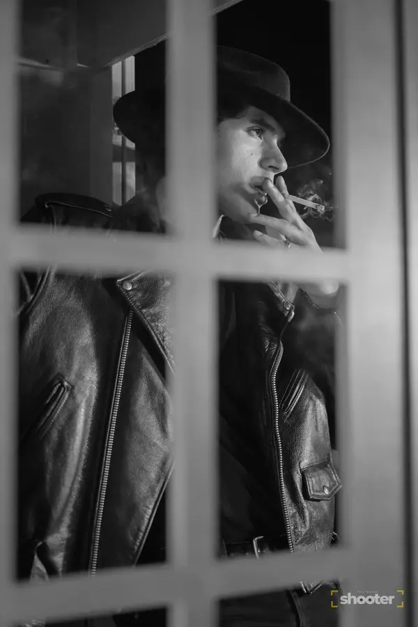 Black-and-white portrait of a man smoking behind a window