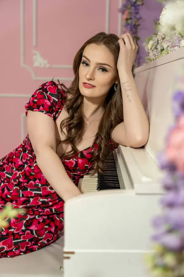 Woman in a floral dress leaning on a white piano