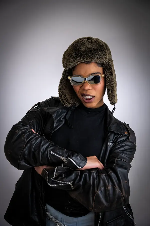 Studio portrait of a model in a fur hat, sunglasses and leather jacket
