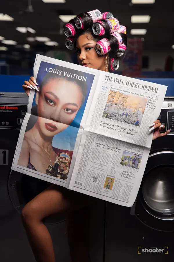 Editorial portrait of a woman in hair rollers reading a newspaper in a laundromat