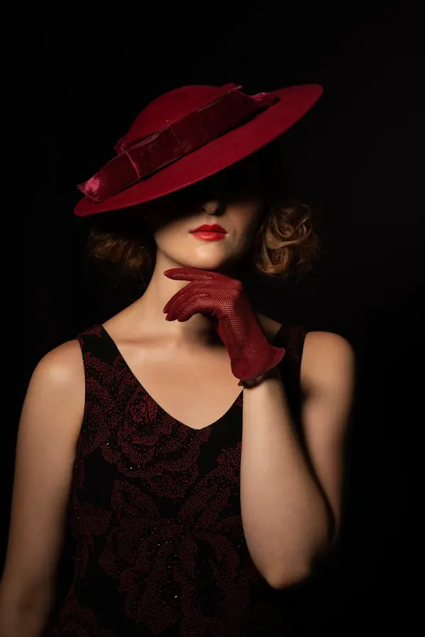 Dramatic low-key portrait of a woman in a red hat and gloves