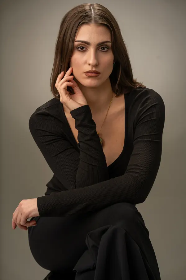 Seated portrait of a woman in black on a warm grey backdrop